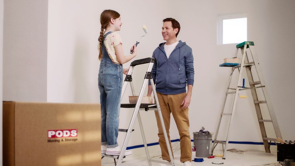 A young girl helps her dad paint walls in their new home as a DIY home improvement project.
