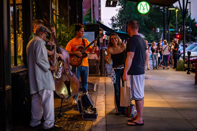 Musicians perform on the sidewalk in Old Market — one of the best Omaha neighborhoods — as passersby stop to enjoy the music.