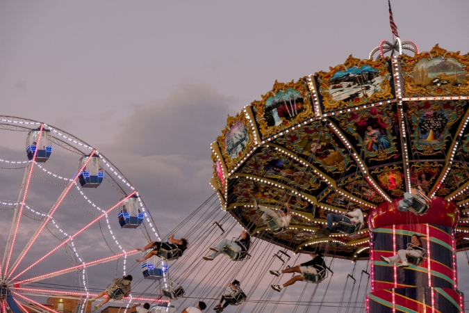 Carnival rides are illuminated as visitors enjoy a sunset view at the Great Allentown Fair — one of many fun things to do in Allentown, PA.
