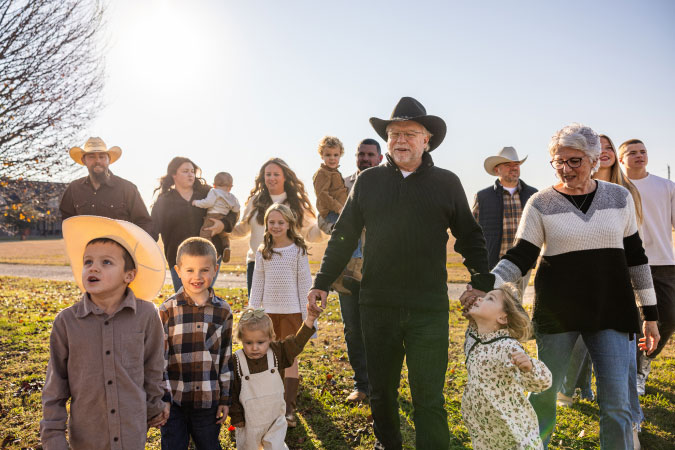A multi-generational family group is walking together across a grassy field in Texas.