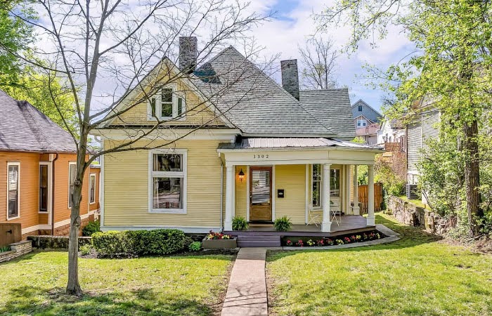 A historic home with a light yellow exterior and a wraparound porch in East End — one of the best neighborhoods in Nashville.