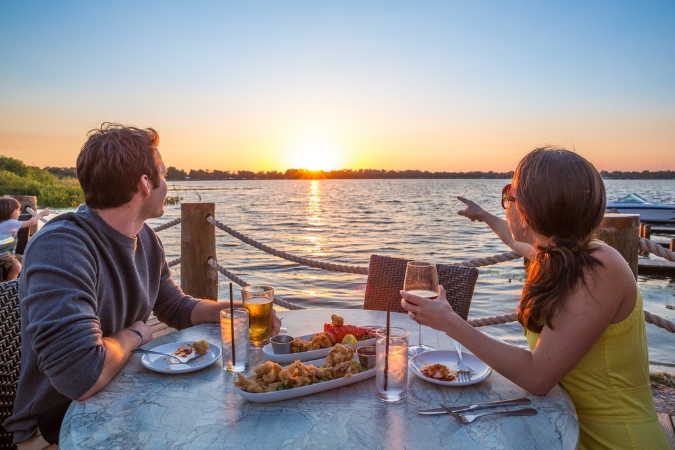 A couple enjoys sunset views at a lakefront restaurant while living in Winter Haven, FL.