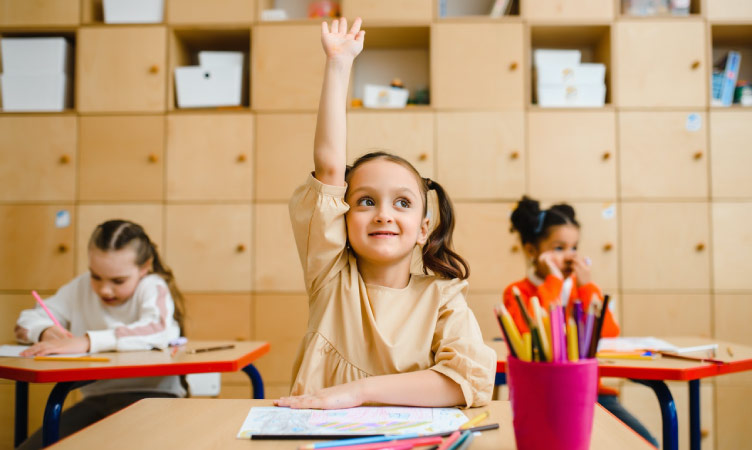A school-age girl raises her hand in class