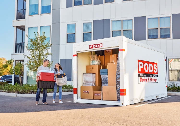 A couple has just begun unloading their PODS container, which is positioned in a parking space outside of their new apartment building.