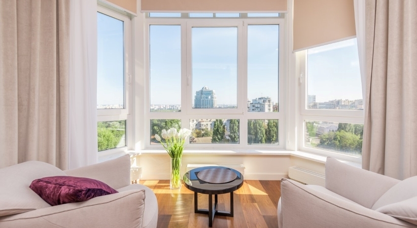 A bay window with the curtains left open to let the light and warmth into the room.