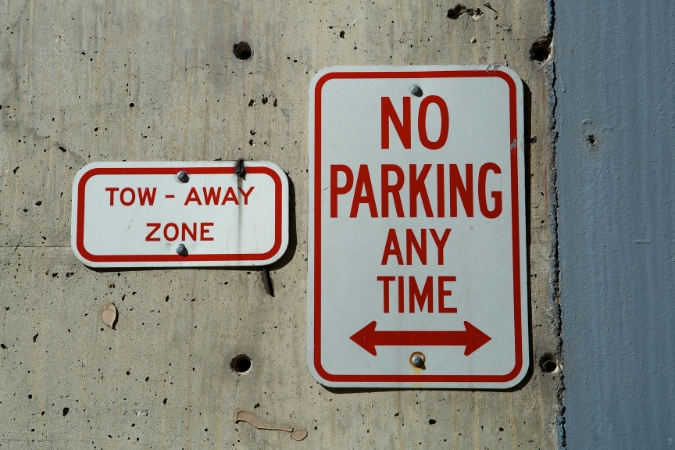 “TOW-AWAY ZONE” and “NO PARKING ANY TIME” signs are posted on a concrete wall, illustrating parking restrictions to keep in mind when arranging portable storage in San Diego.