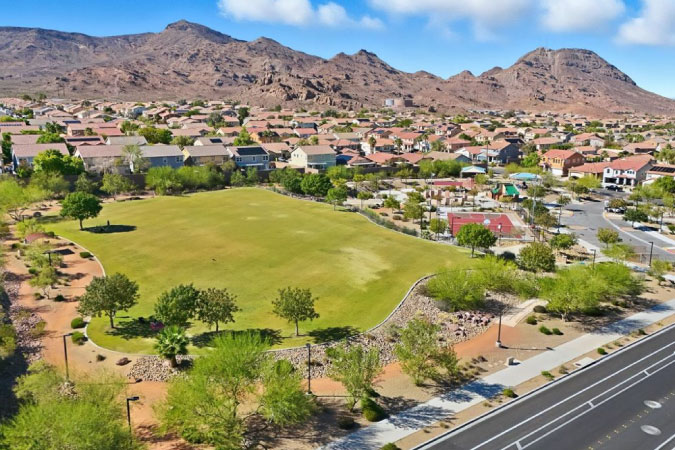 Aerial view of Black Mountain — one of the best neighborhoods in Henderson, NV — featuring a large green field, residential streets, and a nearby mountain range. 