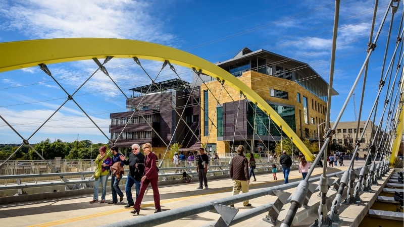 Pedestrians are crossing the beautiful 2nd Street Butterfly Bridge in downtown Austin, TX, on a sunny day.