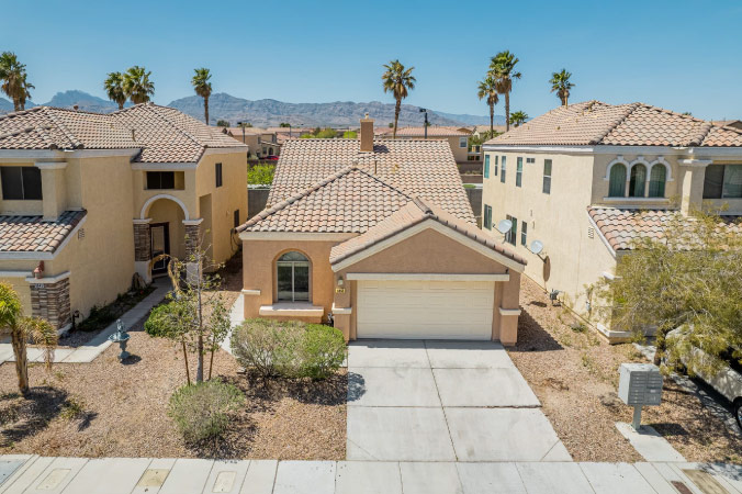 Drone view of a single-family home in Centennial Hills — one of the best places to live in Las Vegas — featuring a stucco exterior, clay tile roof, and mountain views.