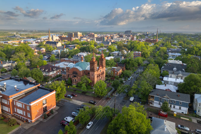 Aerial view of Wilmington, North Carolina, featuring historic churches and the downtown area with lots of greenery.