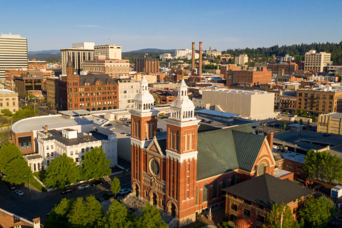 Aerial view of Downtown Spokane, featuring a red-brick church and a variety of other distinct city buildings.