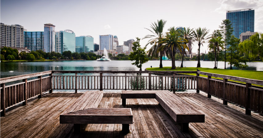 View of city buildings in one of the best neighborhoods in Orlando — Lake Eola Heights — from a wooden deck on a local lake