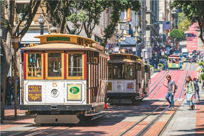 Pedestrians looking to ride the famous street cars cross Powell Street in San Francisco, California.
