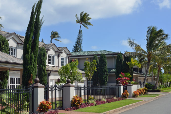 Residential homes in Honolulu, Hawaii, featuring gated yards, lush landscaping, and palm trees.