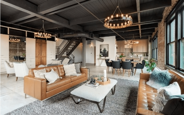 Interior view of a chic warehouse-turned-condominium in Portland’s Pearl District, featuring leather couches, medieval-style chandeliers, and exposed brick. 