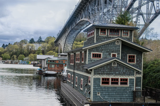 Charming houseboats with wood-shingled exteriors float beneath the Aurora Bridge in Fremont — one of the best neighborhoods to live in Seattle.