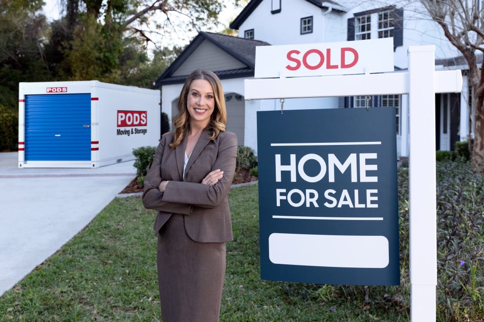 A relator stands in front of a newly sold home with a PODS container in the background. They're a great resource for home selling tips.