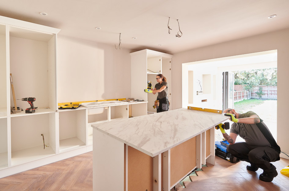 Two professionals are installing cabinets and a kitchen island during a kitchen remodel