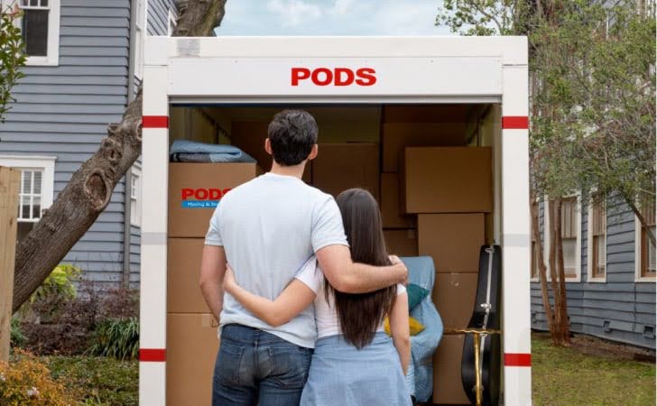 A couple is standing together in front of their loaded PODS moving and storage container in one of the best neighborhoods in Nashville.
