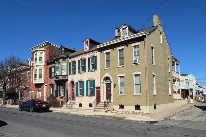 A row of historic brick and stucco townhomes with colorful shutters along a sunny street in historic Downtown — a favorite neighborhood for those living in Allentown, PA.
