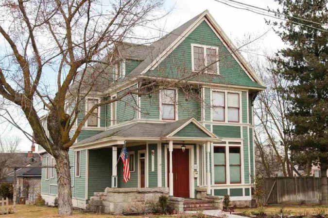 Exterior view of a light green Victorian house in Browne’s Addition — one of the best Spokane neighborhoods — featuring a small side porch and covered entrance.