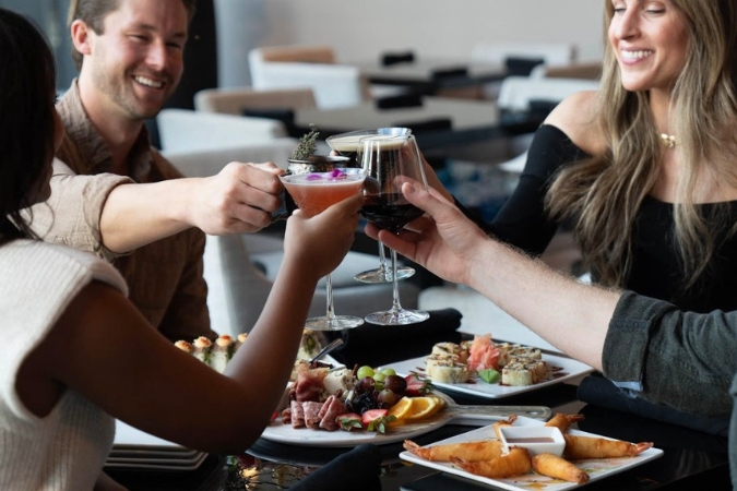 Four people around a table raising a toast over their dinner at The Rutledge, a modern American restaurant in Franklin, TN.