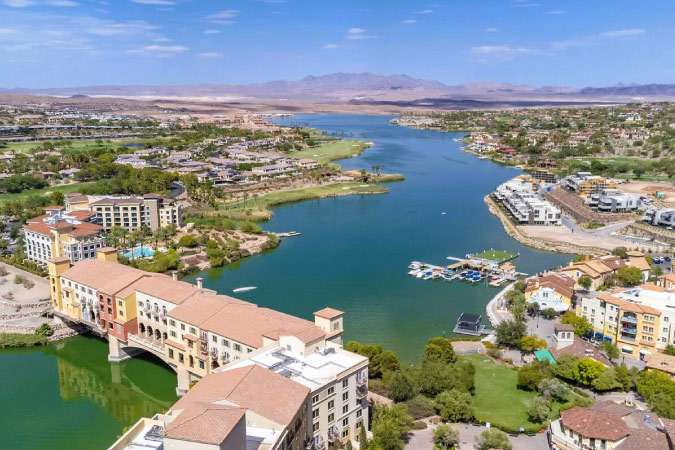 Aerial view of Lake Las Vegas — one of the best neighborhoods in Henderson, NV — featuring waterfront properties and a view of the distant mountains.