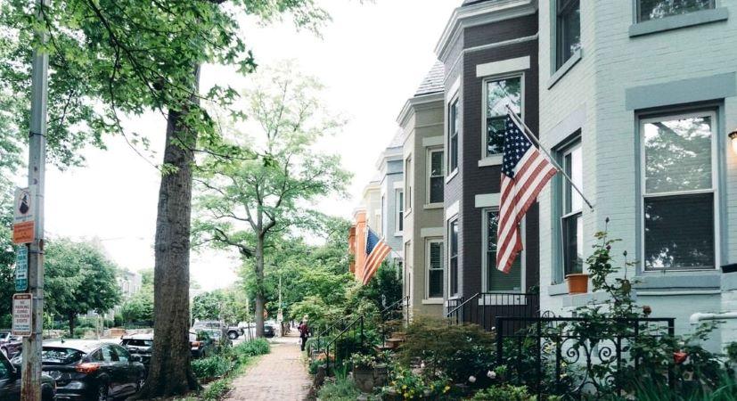 A row of brick townhouses in the Capitol Hill neighborhood of DC. The homes are painted in different neutral colors, including white, black, and beige.