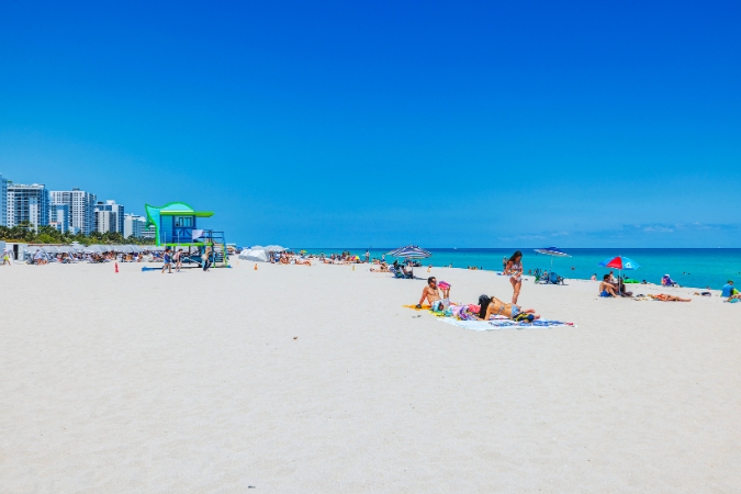 Beachgoers along Miami Beach in Florida — one of the best Southern states to live in — enjoy a sunny day with clear skies.