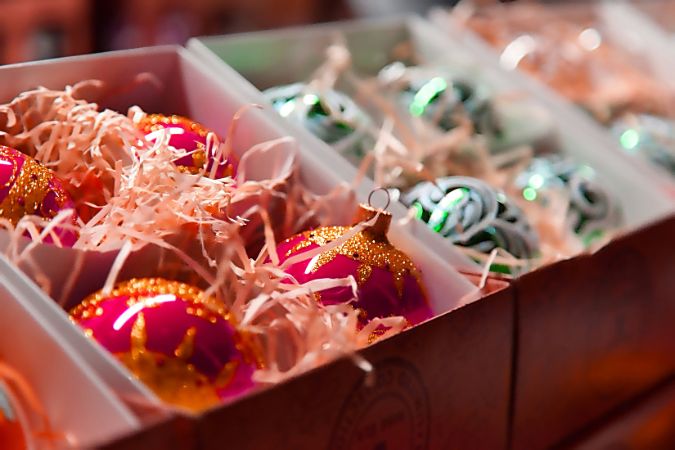Colorful Christmas ornaments packed in shredded paper inside divided storage boxes, ready for seasonal storage.