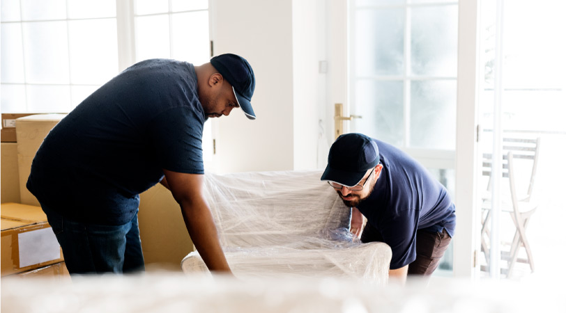 Two professional movers work together to lift a heavy chair during a move.