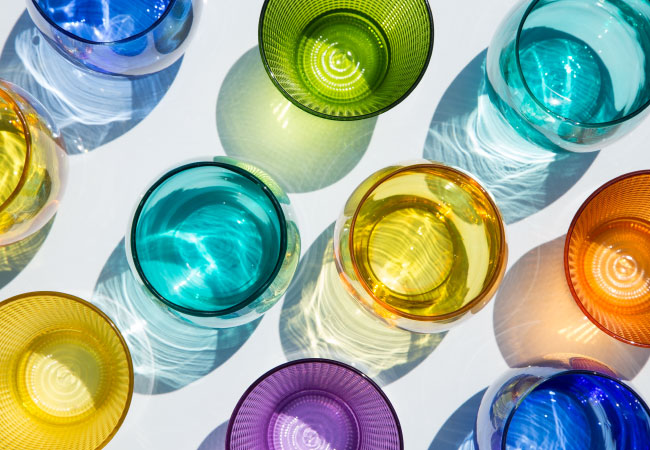 View from above of eleven brightly colored drinking glasses.