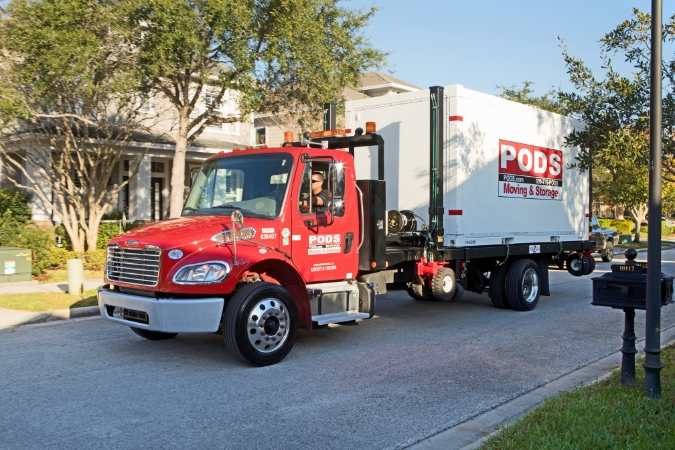 A PODS driver transports a portable moving container through a quiet residential neighborhood in one of the states people are moving out of.
