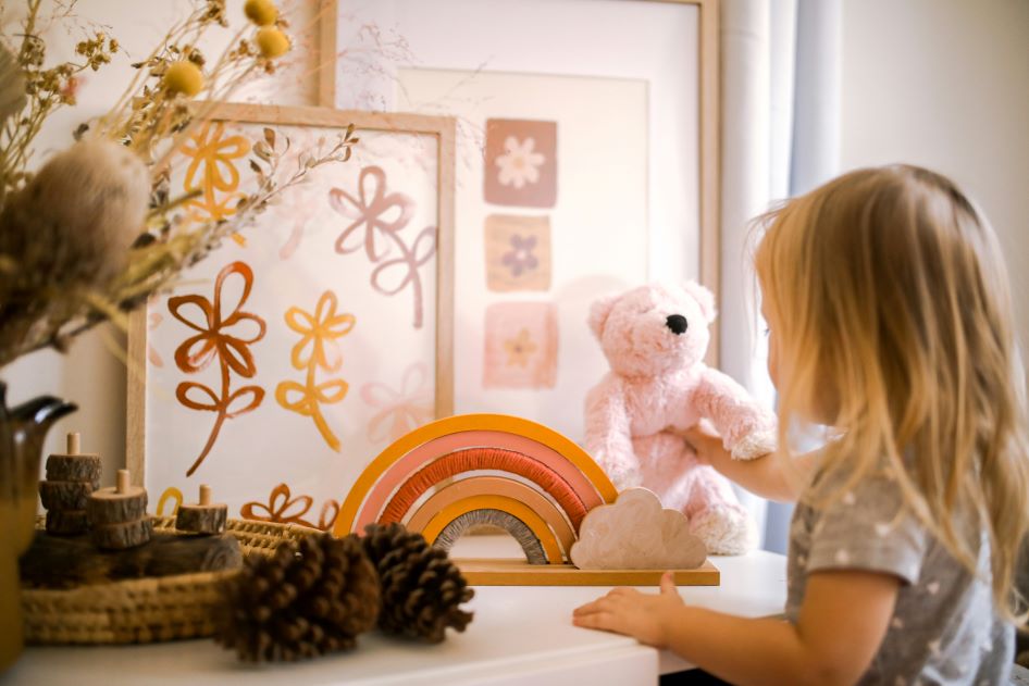 A young girl places a teddy bear in her newly redecorated bedroom. Redecorating your kid's room is a great way to help them adjust to moving.