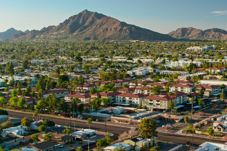 Aerial view of residential neighborhoods in Scottsdale, Arizona, with the mountains filling the skyline in the distance.