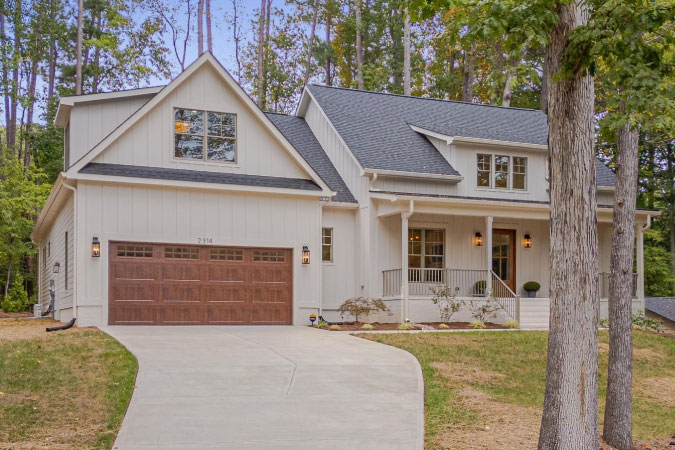 A modern farmhouse home in Durham’s Hope Valley neighborhood, featuring a two-car garage, covered porch, and curved driveway.