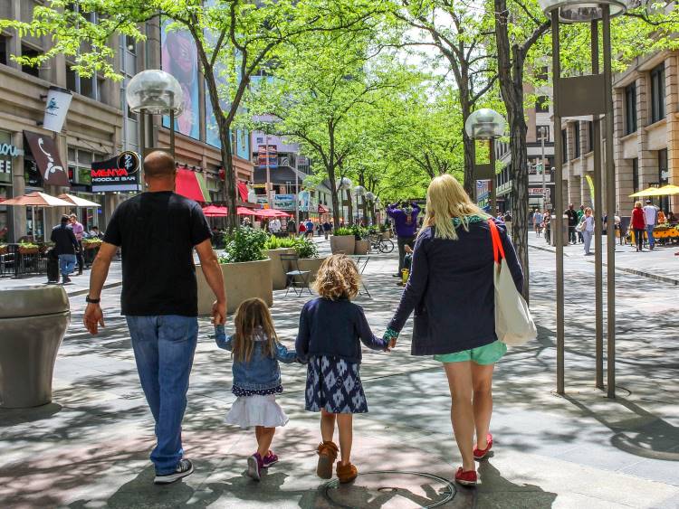 A family holding hands as they walk the sidewalks of downtown Denver