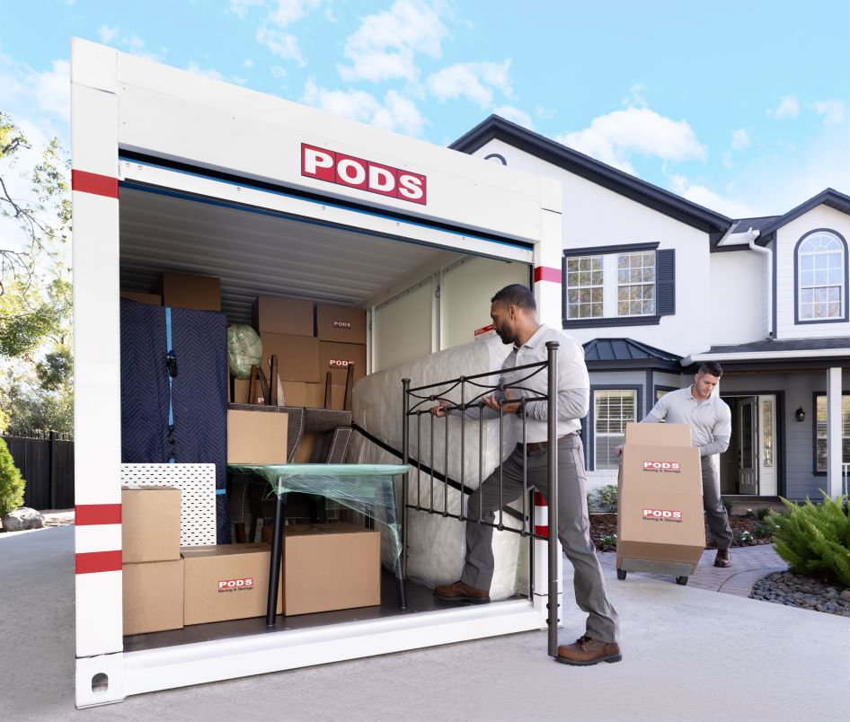 Two movers pack a loaded PODS container as they help a family downsize their home and prepare to store their items.