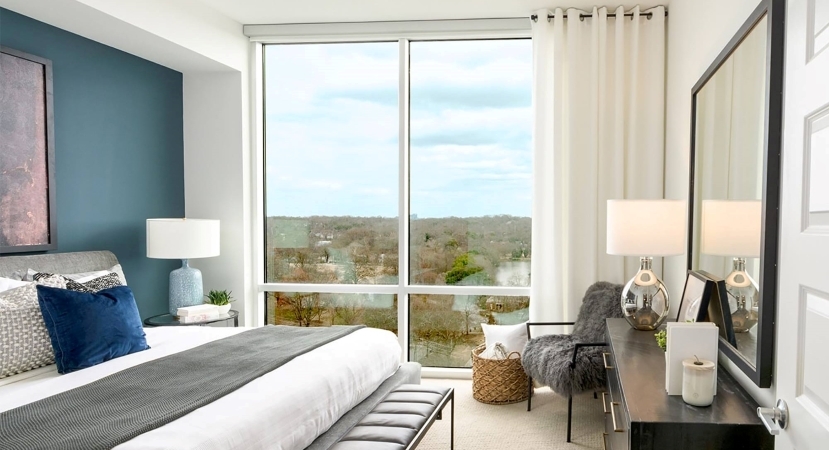 The interior view of a bedroom in one of Piedmont House’s apartments in Atlanta, Georgia. The room features a floor-to-ceiling window looking out over Piedmont Park.