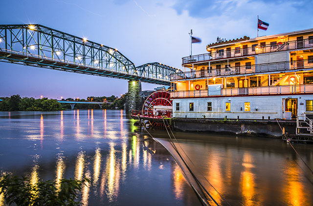 The Southern Belle Riverboat traversing down the Tennessee River, under the bridge, at sunset.