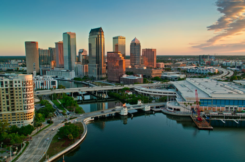 Aerial view of downtown Tampa and the waterfront at sunset with Tampa suburbs visible in the distance