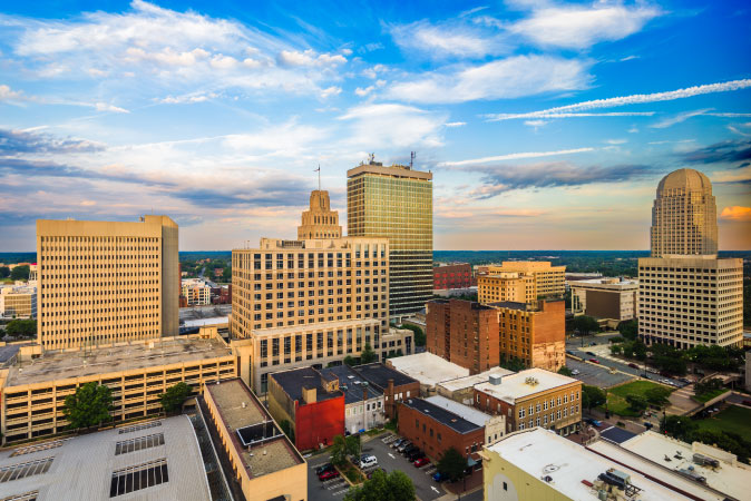 Aerial view of Downtown — one of the best Winston-Salem neighborhoods — featuring a mix of city buildings from three-story warehouses to tall glass structures.