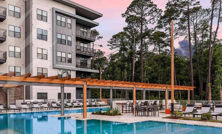 The impressive community pool at JTB Apartments in Jacksonville, Florida, featuring pristine patio furniture and decorative shade