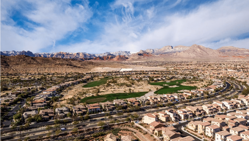 Aerial view of the Summerlin community in Las Vegas, Nevada. Rows upon rows of large residential homes line the streets, and there are mountain ranges in the distance. 