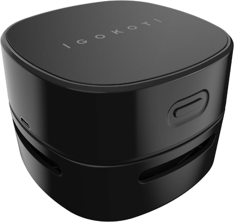 One of the more practical white elephant gift ideas — a black desk vacuum cleaner with rounded-square corners, a power button on the front, and the brand name “IGOKOTI” written on the top.