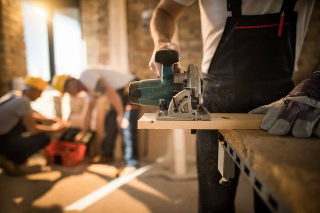 A man on a construction site sawing wood