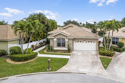 A bird’s-eye view of a tan home in West Palm Beach, Florida. It sits between two homes in a nice, well-manicured neighborhood.