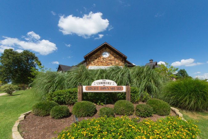 A sign planted in a grassy spot welcomes visitors to The Commons Town Square in Argyle, Texas — one of the towns near Dallas.