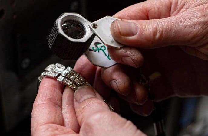 A professional is appraising a piece of jewelry to help determine how much it should be listed for in an estate sale.