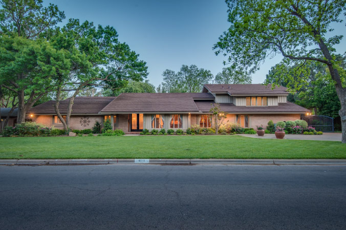 A mid-century modern home in Rush — one of the best Lubbock neighborhoods — featuring a multi-level, frontward sloping roof and a lush green lawn.
